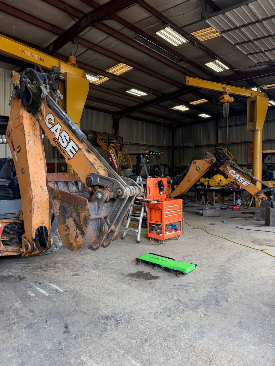 Backhoe booms under the jib cranes inside the Arch Machinery shop in Cypress