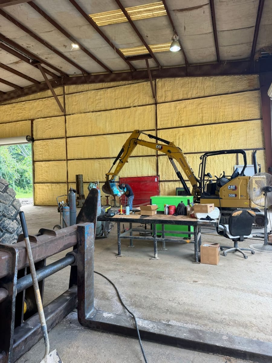 Technician welding next to a Cat 306 mini excavator in the Arch Machinery shop